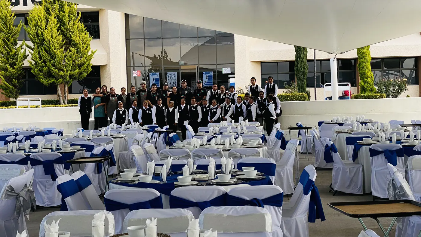 Evento de gran formato al aire libre con mesas vestidas y personal uniformado