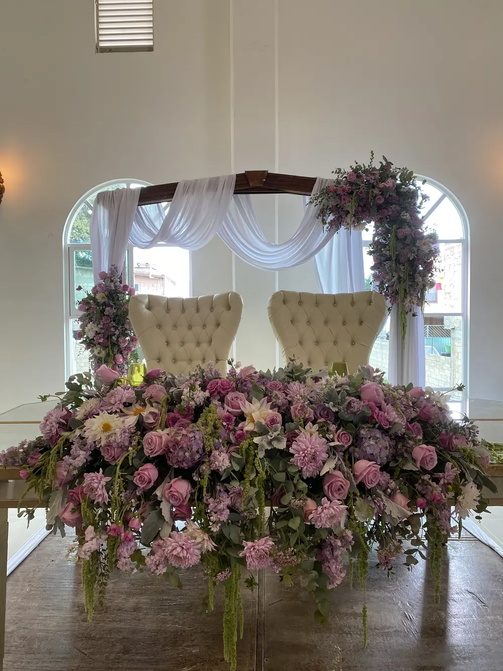 Mesa de honor con sillones capitonados y arreglo floral rosa