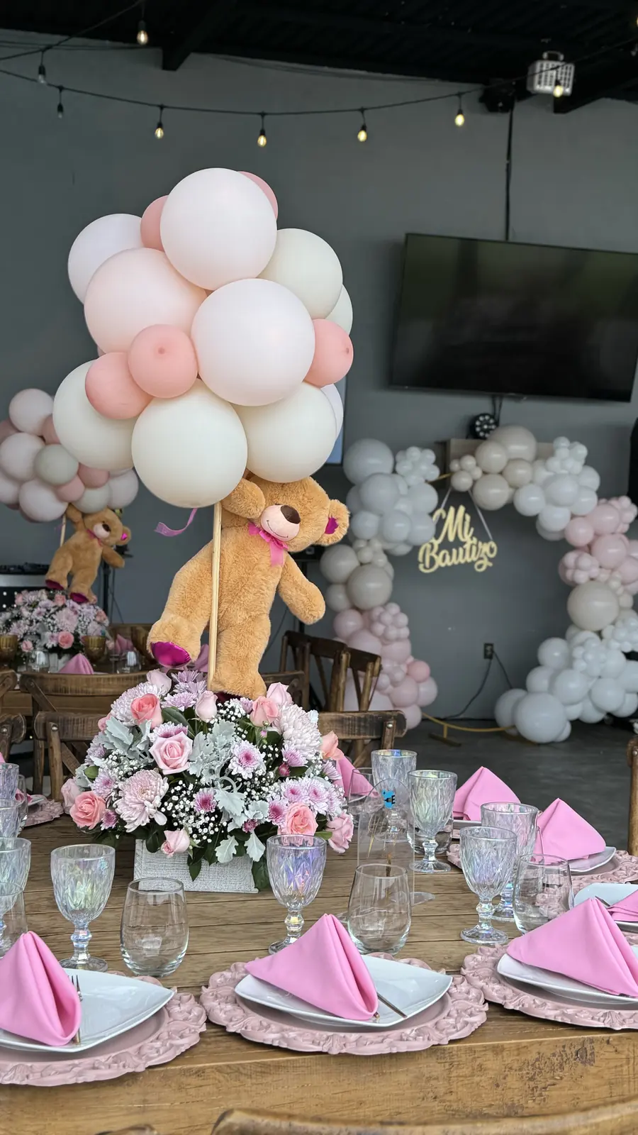 Arreglo de globos rosas con osito sobre mesa con servilletas rosas