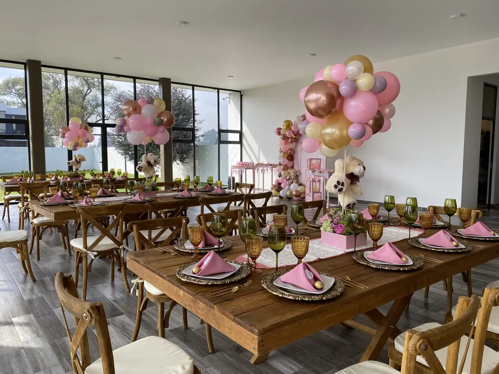 Mesas imperiales con globos y servilletas rosas para una fiesta